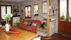 Un salon chaleureux avec une table à manger en bois, un canapé rouge et des coussins à motifs.
