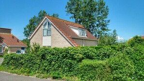 A two-story house with a pitched roof, a visible chimney, and a satellite dish. - Bungalow in Breskens near Beach & Lighthouse (Breskens)