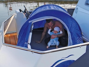 A tent on a boat with a man and a child inside. - Houseboat on the Peene, Demmin (Demmin)
