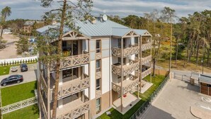 A multi-story building with balconies, a parking area, and a surrounding landscape. - Spacious Apartment in Mielno With Private Terrace (Mielno)