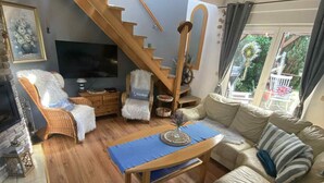 A living room with a wooden staircase, a sofa, a coffee table, and a TV. - Holiday Home in Kolczewo Near Wild Beach (gmina Wolin)