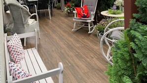 A covered patio with wooden flooring, white wicker furniture, and red roses hanging from the ceiling. - Holiday Home in Kolczewo Near Wild Beach (gmina Wolin)