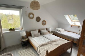 Une chambre avec deux lits, une lucarne, un attrape-rêves et une vue sur la verdure environnante.