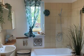 A bathroom with a bathtub, shower, and a window with a curtain. - Holiday Home in Kolczewo Near Wild Beach (gmina Wolin)