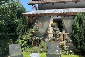 A covered outdoor seating area with chairs and tables, surrounded by greenery and potted plants. - Holiday Home in Kolczewo Near Wild Beach (gmina Wolin)