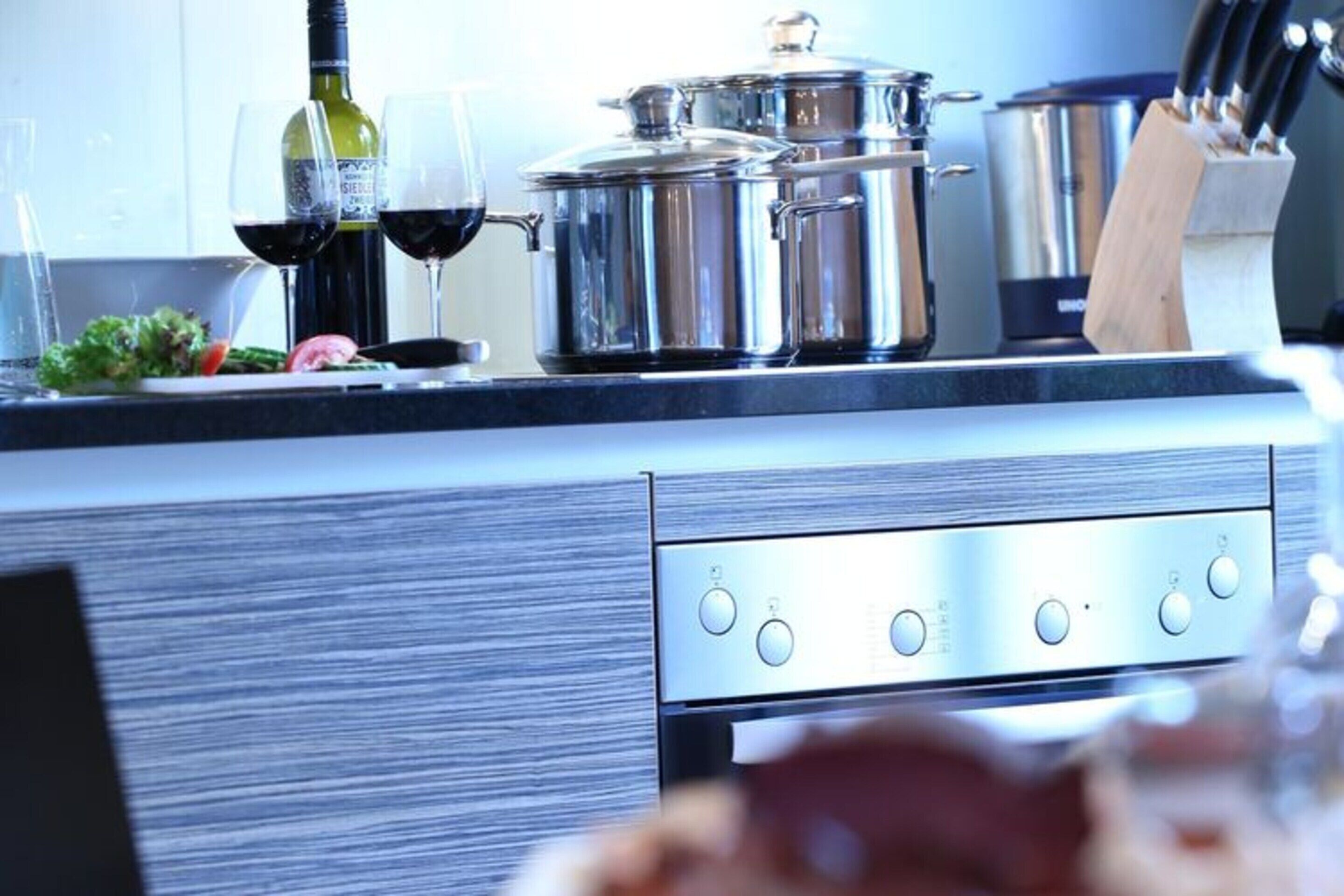 A modern kitchen with stainless steel appliances, a wine bottle, and glasses.