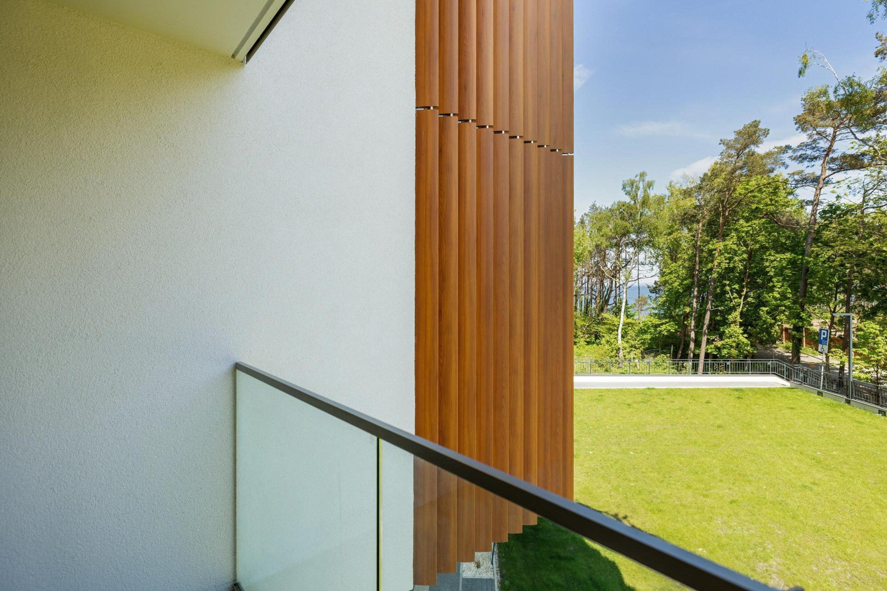 Un edificio moderno con un pilar de madera y una barandilla de vidrio.