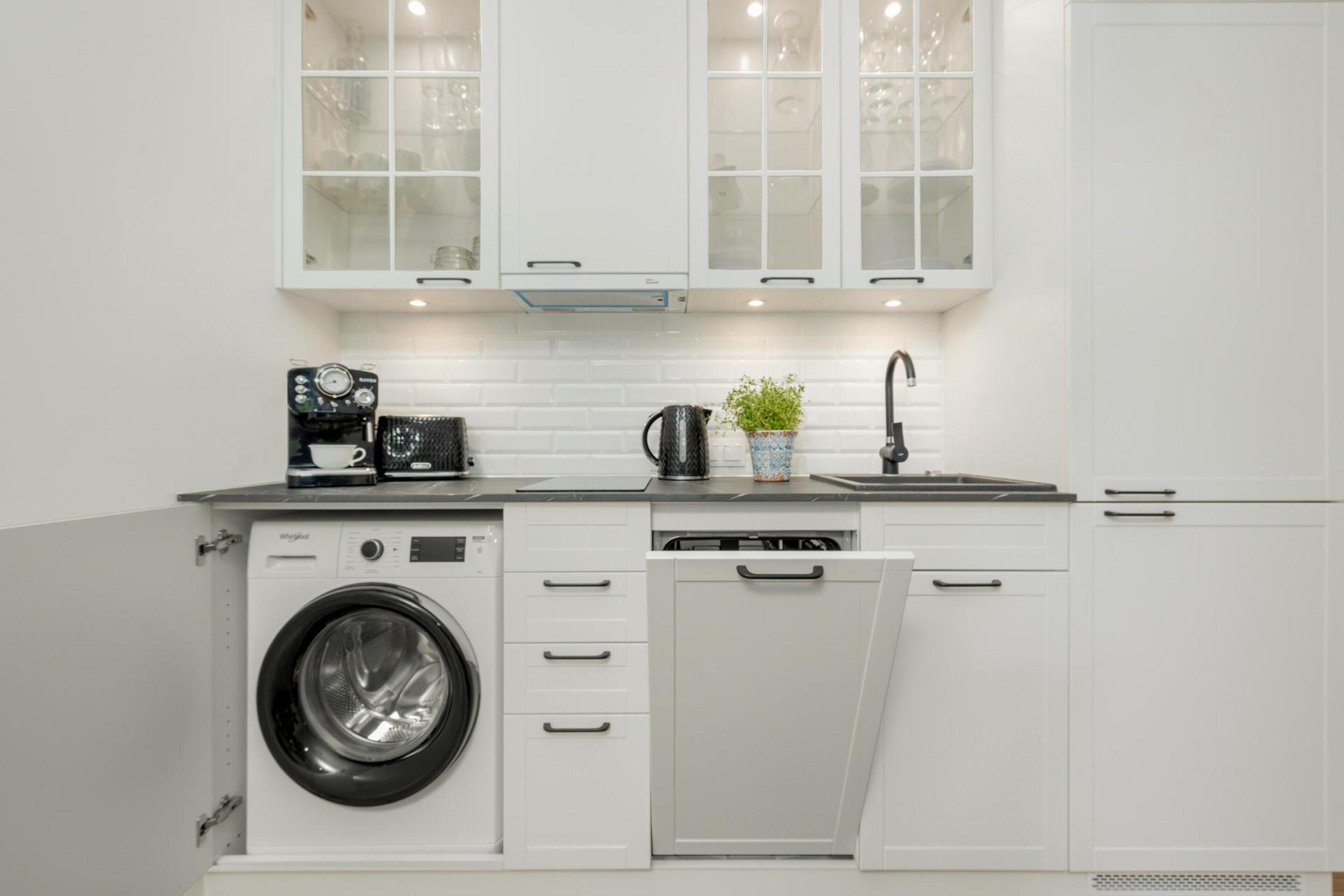A compact kitchen with a washing machine, a coffee maker, and a sink.