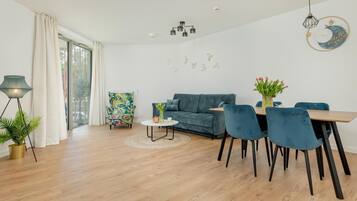 A modern living room with a sofa, chairs, a coffee table, and a dining area.