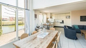 Àmplia zona d'estar amb taula de dinar, sofà i vista al riu.