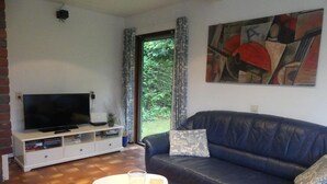 A living room with a TV, sofa, and a painting on the wall. - Family & Pet-Friendly Escape (Breskens)