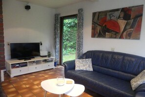 Uma sala de estar com televisão, sofá e um quadro na parede.