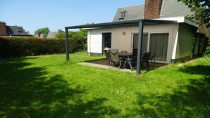 A covered patio with a table and chairs, a small window, and a door. - Family & Pet-Friendly Escape (Breskens)