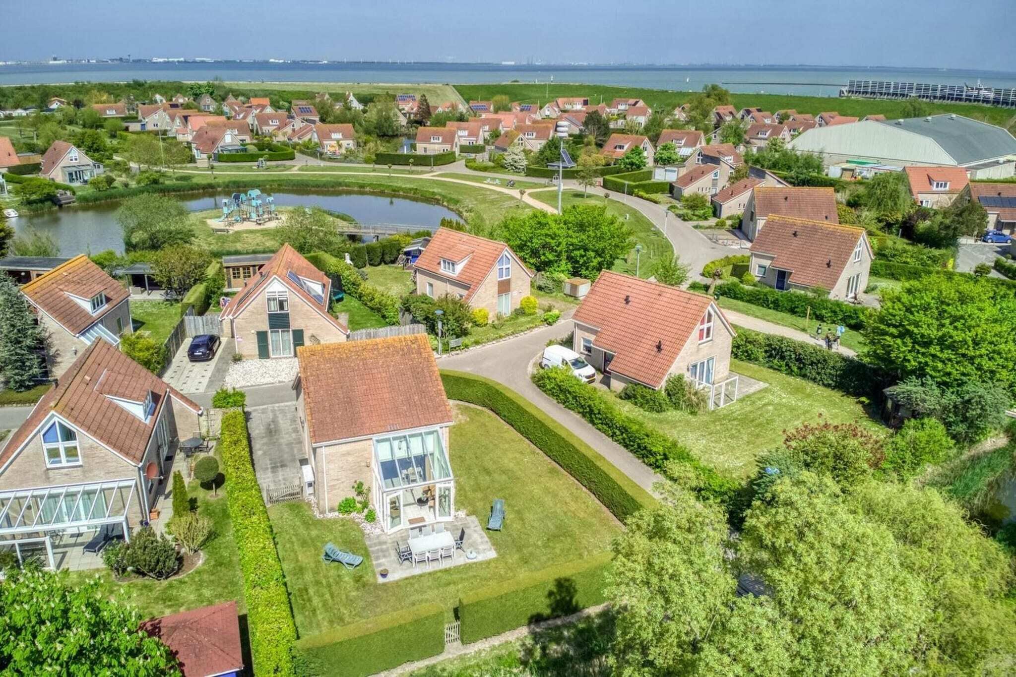 Een woonwijk met huizen, een meer en een brug op de achtergrond.