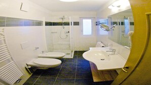 Un baño con dos lavamanos, una ducha y un inodoro.