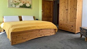 Un dormitorio con una cama de madera, un armario y un cuadro en la pared.