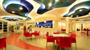 En modern restaurang med röda stolar och bord, en bardisk med en blå bakgrund och en unik takdesign.