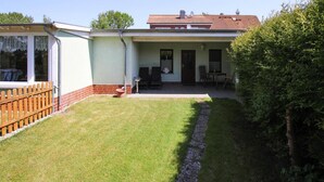 A two-story house with a covered patio, a fenced yard, and a small garden area. - Doppelhaushalfte, Plau am See (Plau am See)
