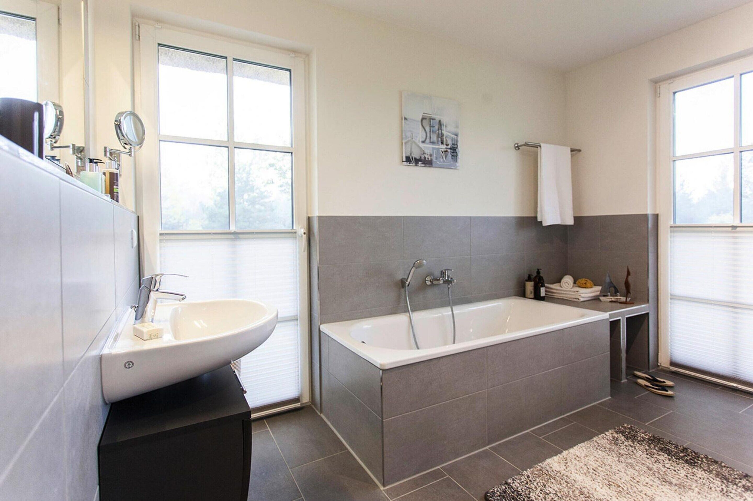 Un baño moderno con una bañera grande, un lavabo y un espejo.