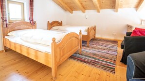 A bedroom with two wooden beds, a colorful striped rug, and a black sofa. - Chalet Hochkrimml With Sauna on the ski Slope (Krimml)