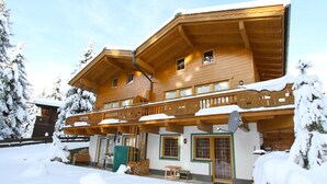 A wooden chalet with multiple balconies and a covered porch, surrounded by snow. - Chalet Hochkrimml With Sauna on the ski Slope (Krimml)