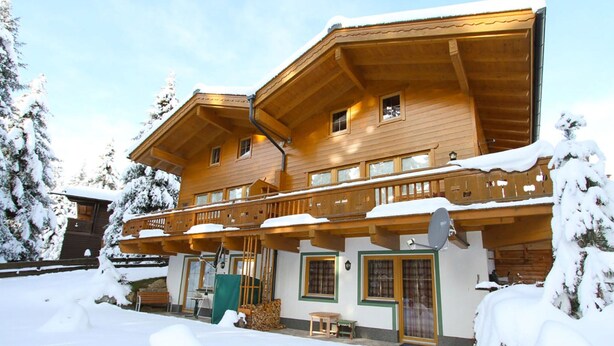 A wooden chalet with multiple balconies and a covered porch, surrounded by snow. - Chalet Hochkrimml With Sauna on the ski Slope (Krimml)