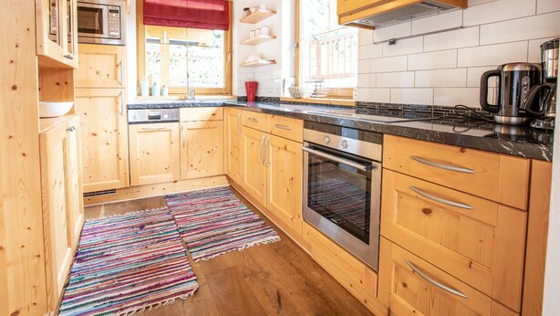 A kitchen with wooden cabinets, a stainless steel oven, a microwave, and a coffee maker. - Chalet Hochkrimml With Sauna on the ski Slope (Krimml)