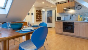 A modern kitchen with wooden cabinets, a microwave, and a clock on the wall. - Wohnung in St.peter Ording (St. Peter-Ording)