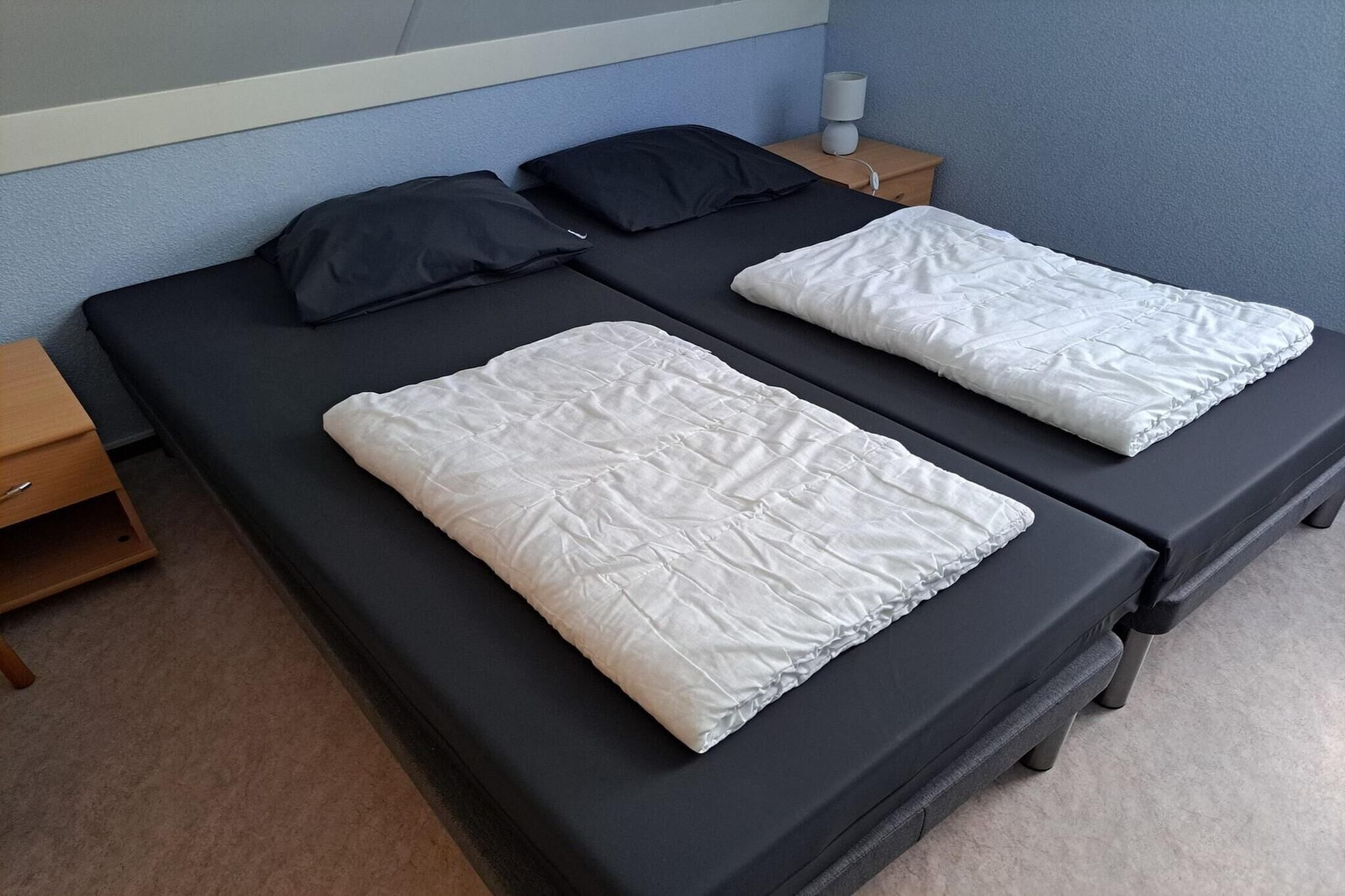 A double bed with black and white bedding, a bedside table with a lamp, and a wooden nightstand.