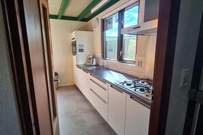 A kitchen with a gas stove, a sink, and cabinets.
