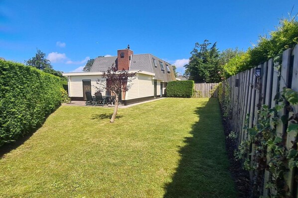 A house with a sloped roof, a chimney, and a well-maintained lawn.