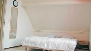 A bedroom with a bed, a nightstand, a wall clock, and a mirror. - Waterfront Bungalow Near Beach (Breskens)