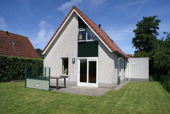 A two-story house with a sloped roof, a balcony, and a sliding glass door.