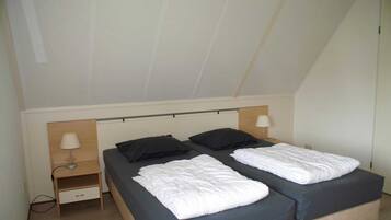 Ein Schlafzimmer mit zwei Betten, einem Nachttisch und einer Lampe.