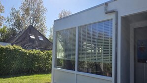 Un edificio moderno con grandes ventanales, fachada blanca y césped cuidado.