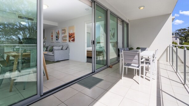 Un salon moderne avec un canapé, une table à manger et un balcon doté d’une balustrade blanche.