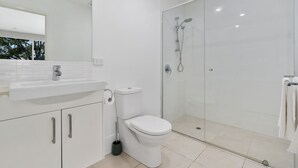 Une salle de bain moderne avec une douche à parois de verre, des toilettes et un lavabo avec un miroir au-dessus.