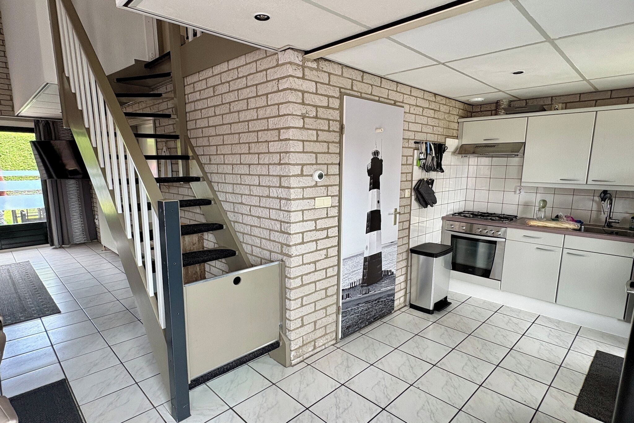 A modern kitchen with white cabinets, a stainless steel stove, and a brick accent wall.