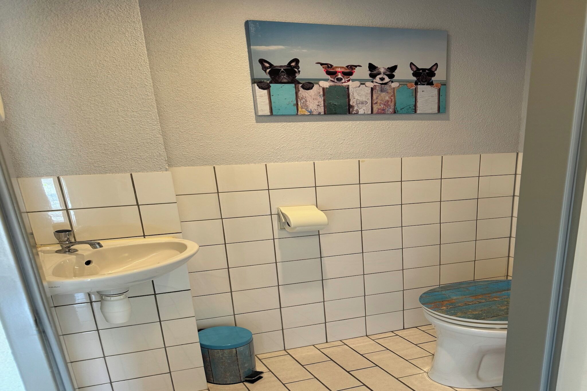 A bathroom with a sink, toilet, and a wall-mounted toilet paper holder.