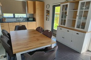 A compact kitchen with a dining table, chairs, cabinets, and a window.