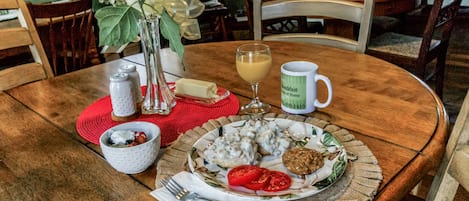Una mesa de madera con un plato de comida, un vaso de jugo y un florero con flores.