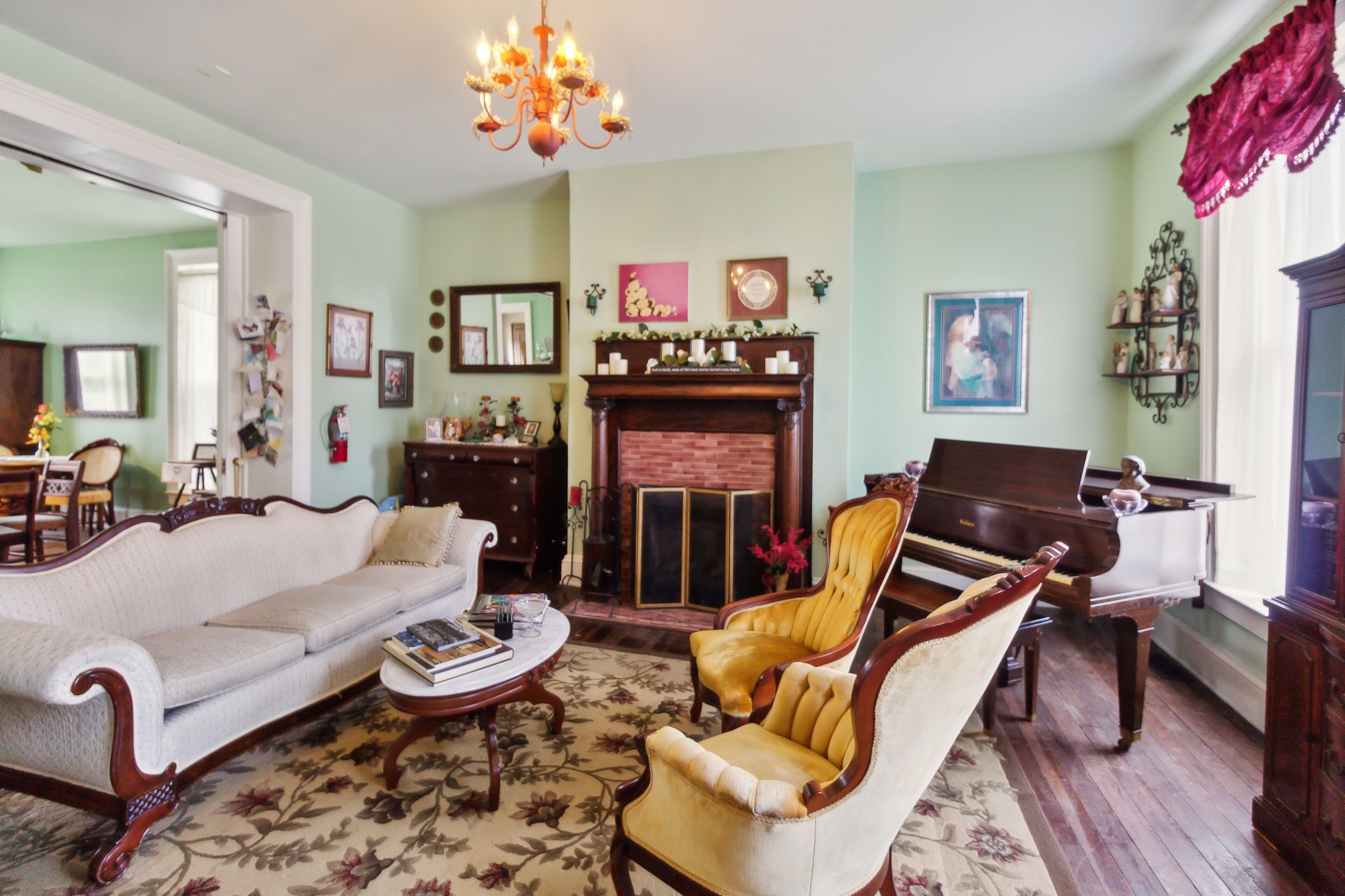 A living room with a sofa, armchairs, a coffee table, a fireplace, and a piano.