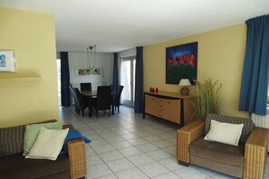 A living room with a sofa, armchairs, a dining table with chairs, a painting, and a cabinet. - Bungalow in Breskens near the Lighthouse (Breskens)