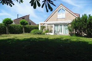 A house with a covered patio, a brick exterior, and a well-maintained lawn. - Bungalow in Breskens near the Lighthouse (Breskens)