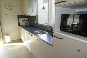 A modern kitchen with a built-in microwave, stainless steel sink, and white cabinetry.