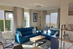 A living room with two blue sofas, a wooden coffee table, and a floor lamp.