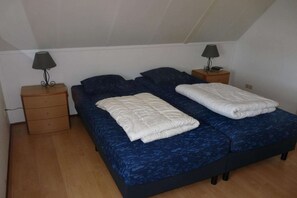 Une chambre à coucher avec un lit, deux tables de chevet et deux lampes.