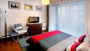 A hotel room with a bed, a chair, a dresser, and a television. - Apartment in Swinoujscie Near the Beach (Swinoujscie)