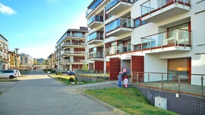A modern apartment building with multiple balconies, a paved pathway, and a clear sky. - Apartment in Swinoujscie Near the Beach (Swinoujscie)