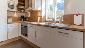 Une cuisine moderne dotée d’appareils électroménagers intégrés, d’une grande fenêtre et offrant une vue sur l’extérieur.